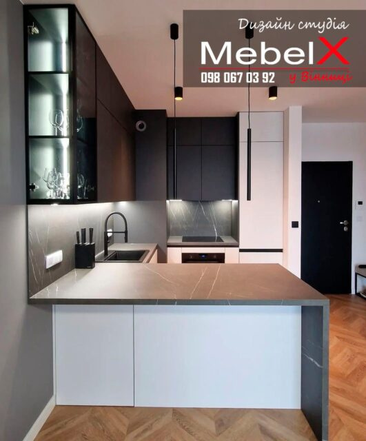 ✅ Кухня на замовлення у Вінниці яка підкорює своєю строгістю, мінімалізмом та елегантністю!Нижня база фасадів і вбудований холодильник виконані матового білого кольору, а стільниця з фартухом завдяки своєму забарвленню під мармур ідеально створюють м'який перехід до чорних верхніх фасадів.У кутку кухні є вентиляційний короб, який ми обіграли кольором і зробили ледь помітним 👌🤗Багато наших замовників вибирають або барну стійку, або окремий, повноцінний острів. Але тут ми вирішили поєднати та виготовили півострів, у якого з одного боку є висувні ящики, а з іншого – місце для сидіння.Зверніть увагу на верхні фасади, вони виготовлені до стелі. З лівого краю ми зробили скляні фасади з врізною підсвічуванням, що надає кухні легкість і легкість.У результаті у нас вийшла ідеальна кухня, яка вже тішить своїх господарів! Як вам наш проект?
___🙌Виготовимо проект будь-якої складності в найкоротші терміни!📨 Пишіть нам у Директ @mebelx_ua📱 Дзвоніть 063-560-11-56⠀